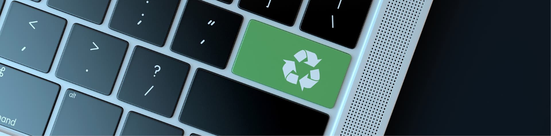 Close-up of a keyboard with a green key featuring a recycling symbol, symbolizing sustainability.