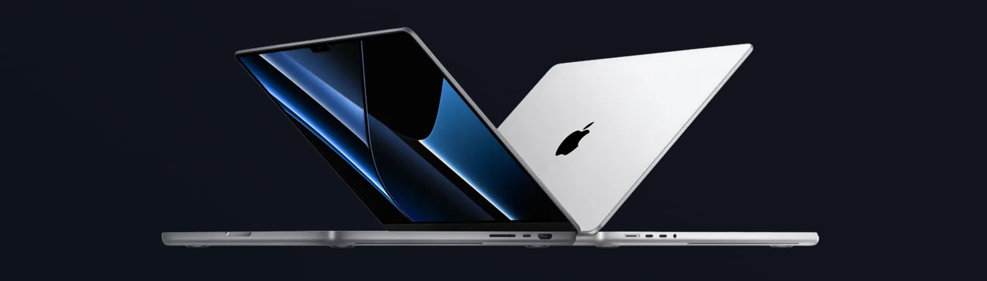 Two sleek laptops, one open showing a vibrant screen, and the other closed, both in a reflective metallic finish, on a dark background.