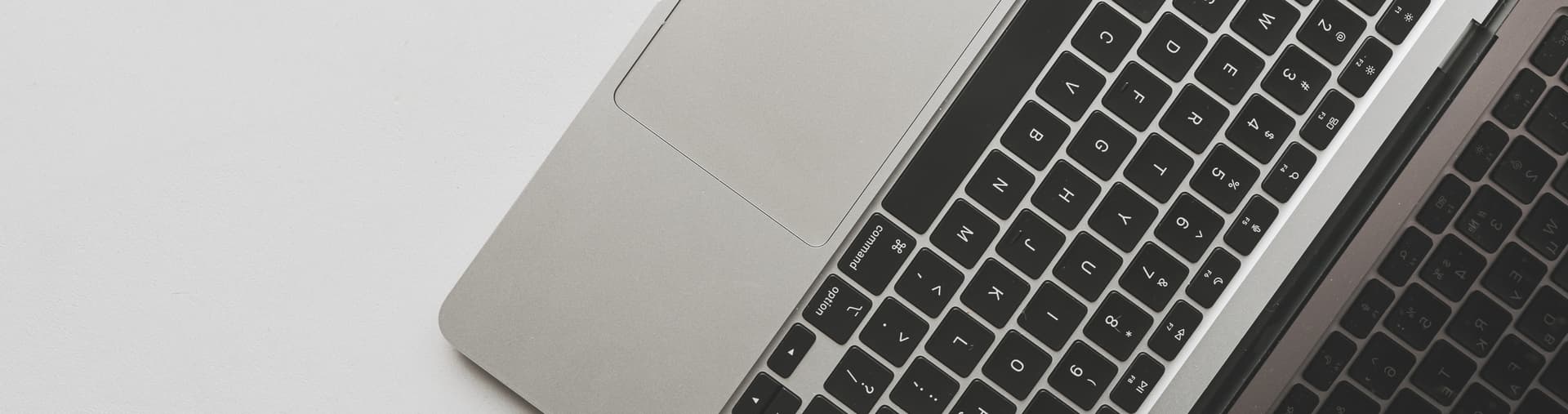 Close-up of an open laptop on a white surface, showing part of the keyboard and touchpad.
